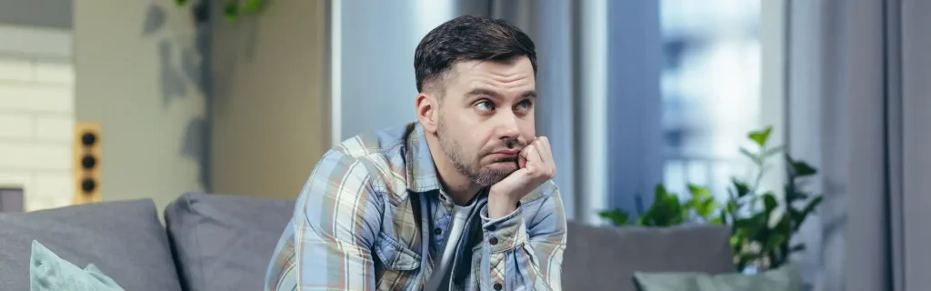 portrait-handsome-young-man-waiting-bored-thought-sits-home-couch-holds-his-head-his-hand-thinks-depression-quarantine