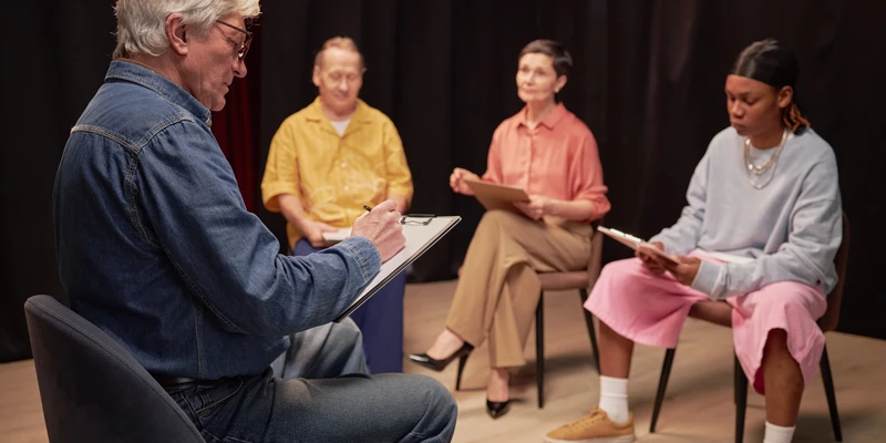 kembali group therapy man blue shirt white socks sits
