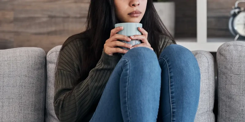 kembali mental health woman sitting couch holding cup