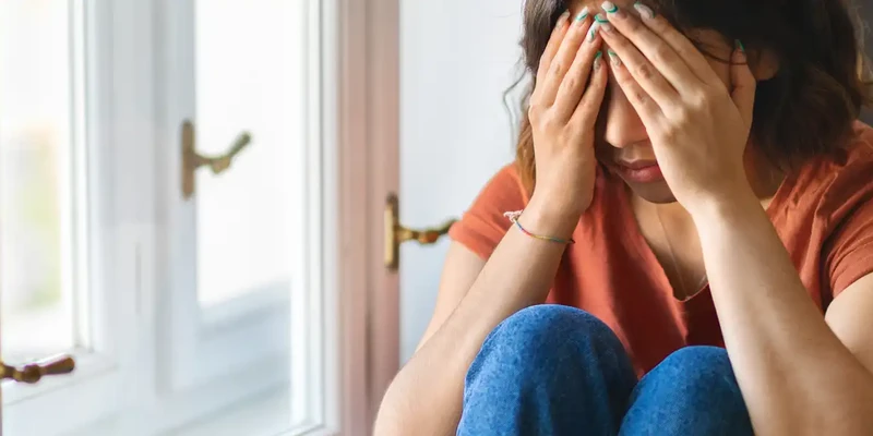 kembali mental health woman sitting floor hands face