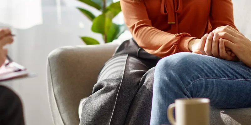 kembali therapy woman sitting couch hands clasped